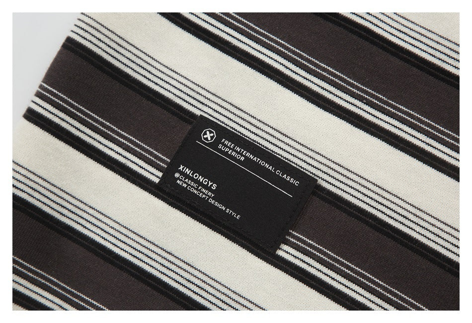 Close-up of a black sewn label on cream and dark brown striped knit fabric.