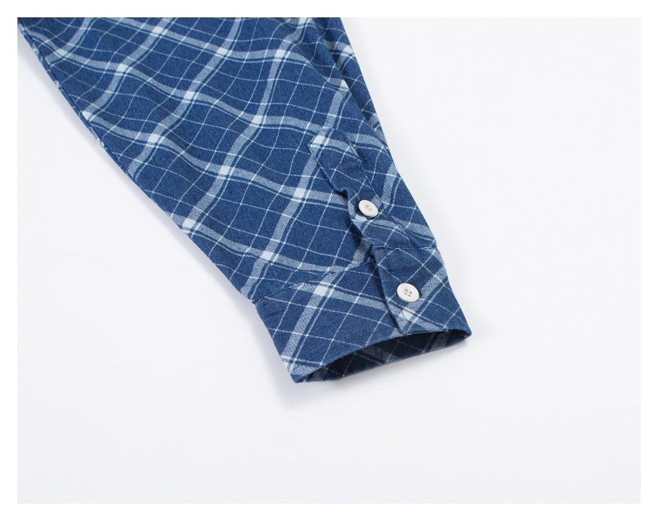 Close-up of a blue-and-white plaid shirt sleeve cuff with two white buttons.