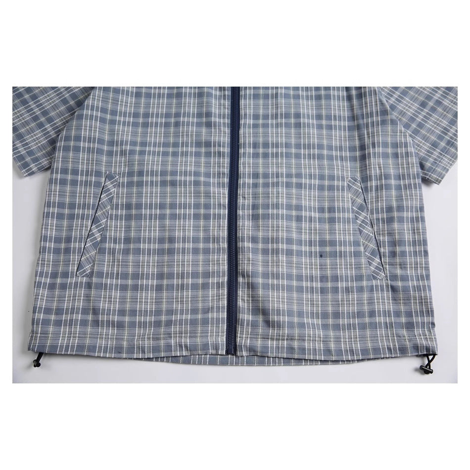 Close view of the blue-gray plaid shirt's front zipper, slanted pockets, and adjustable hem cords.