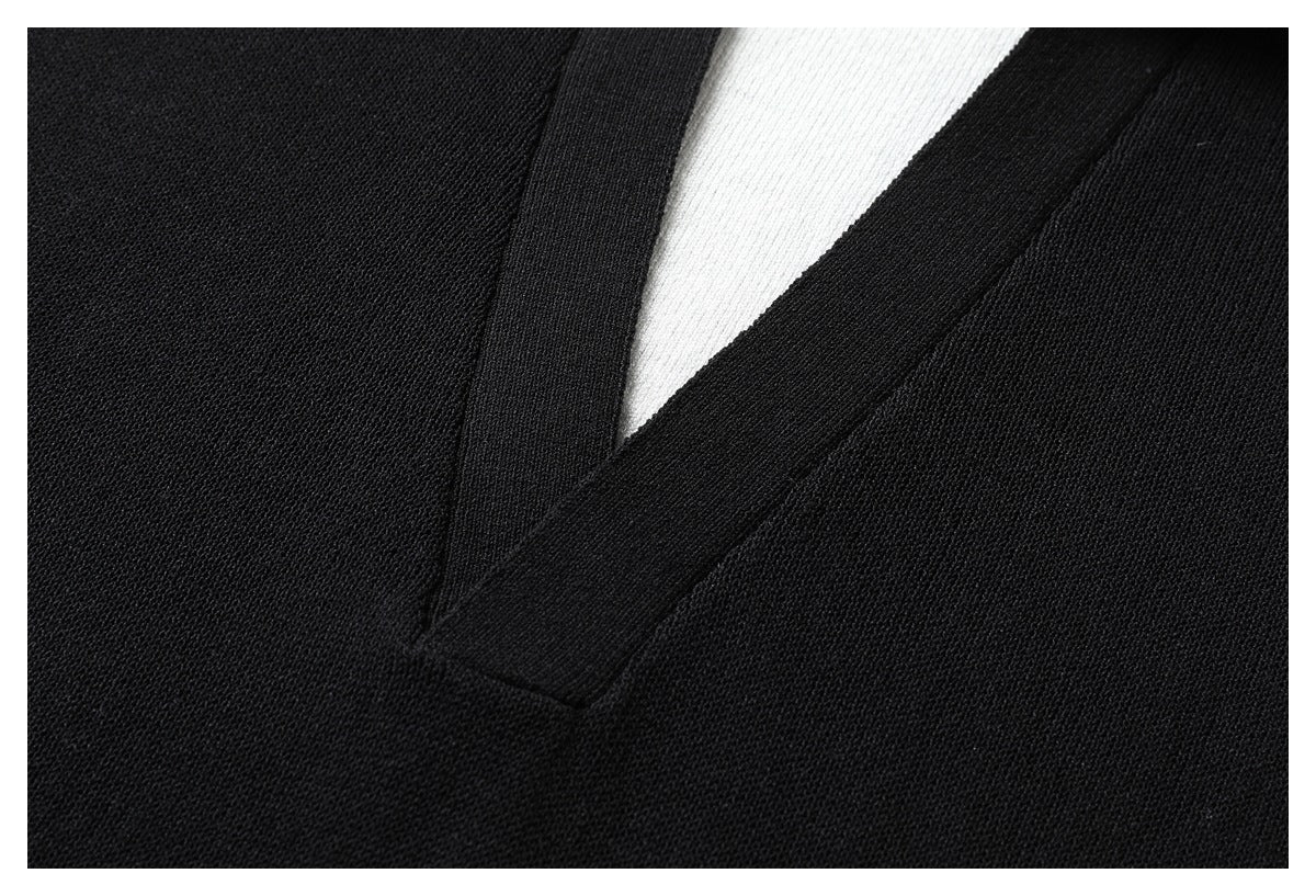 Close-up of the black knit polo's V-shaped neckline trim against its white inner panel.