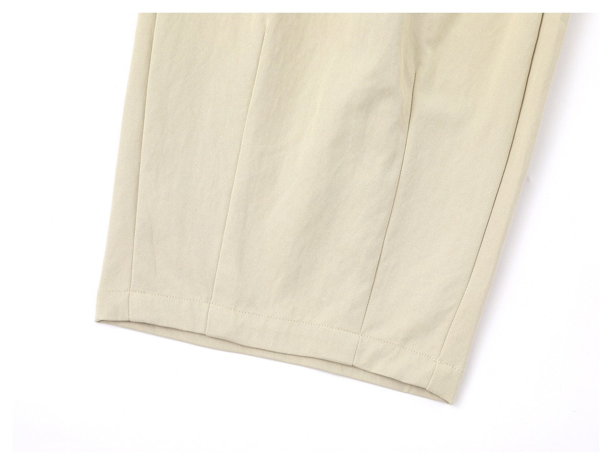 Close-up of a cream trouser leg hem showing stitched panel seams and a folded hem.