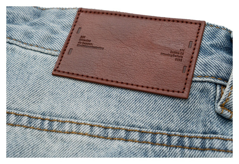 Close-up of a brown leather patch stitched onto the waistband of light-wash jeans.