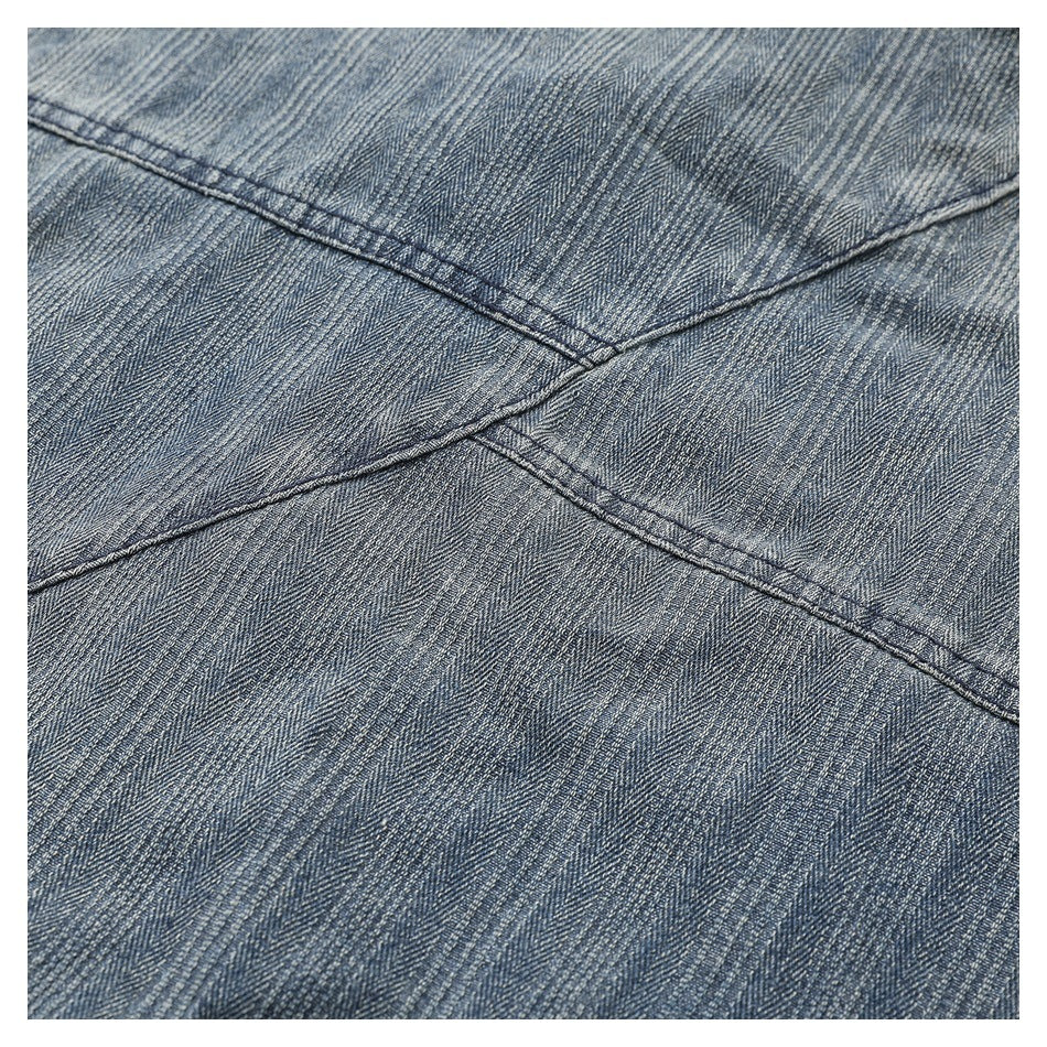 Close-up of intersecting stitched seams on gray-blue striped jacket fabric.