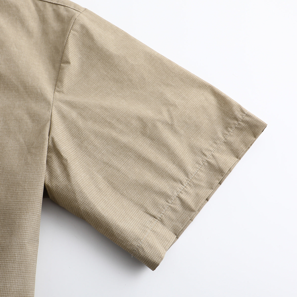 Close-up of the beige micro-check shirt's short sleeve and stitched cuff.