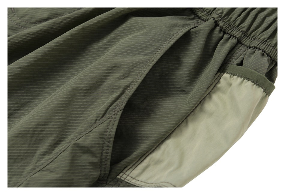 Close-up of an olive shorts pocket opening and pale contrast pocket lining.