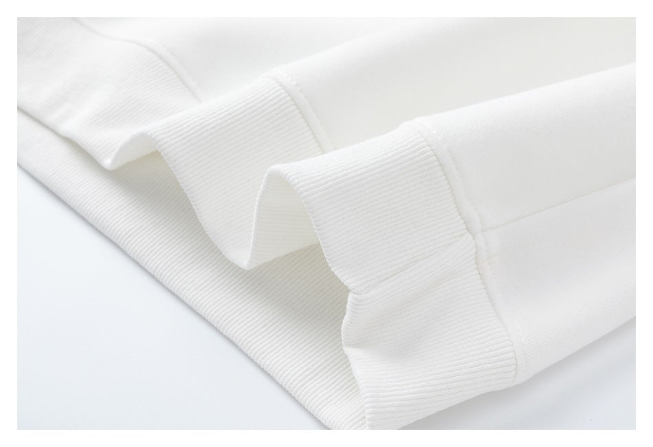 Close-up of ribbed cuffs and stitching on a white sweatshirt laid folded.