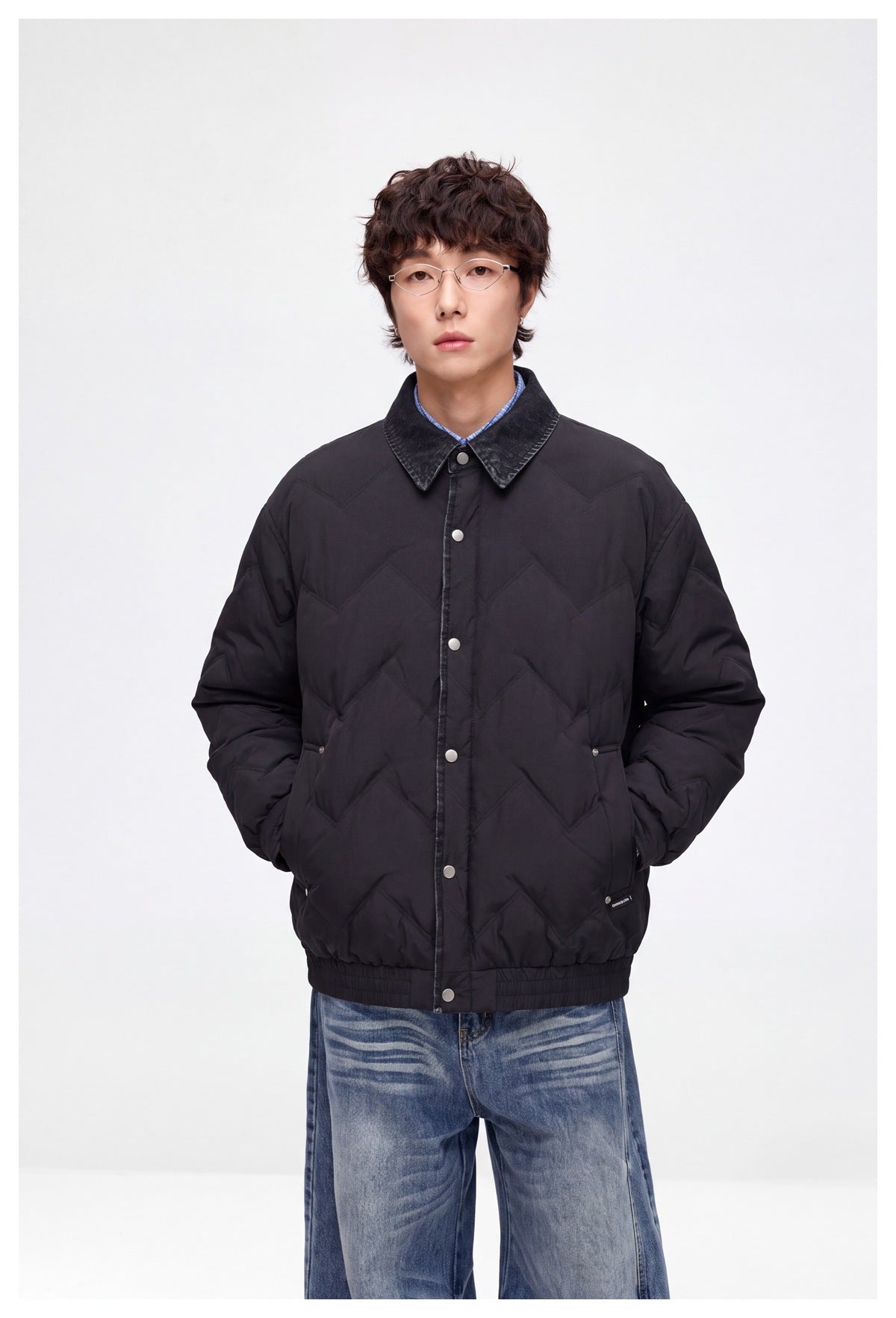 Front view of a model wearing a dark chevron-quilted jacket with a contrast collar, snap closure, and elastic hem.