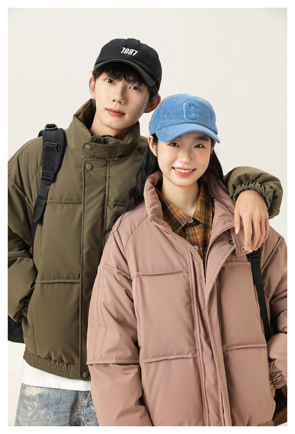 Close view of two models wearing olive green and dusty pink padded jackets with high collars and front closures.
