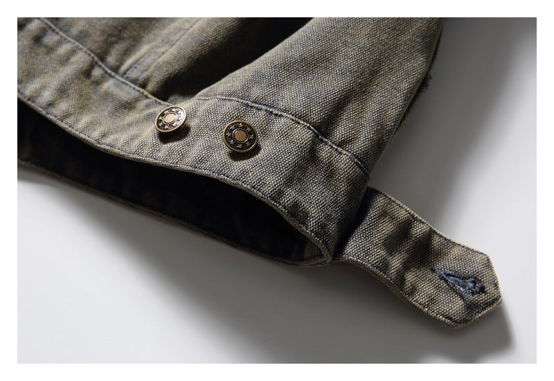 Close-up of a mottled gray-olive garment tab with two round metal buttons and dark stitching.