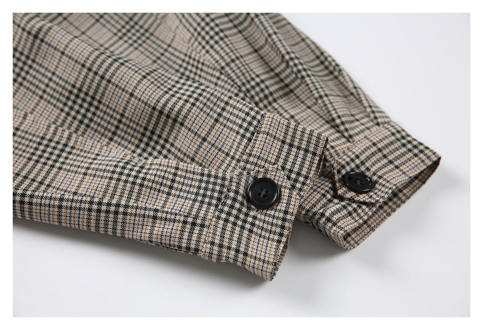 Close-up of black buttons fastening plaid garment cuffs or tabs.
