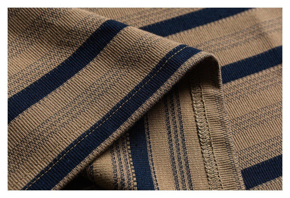 Close-up of a folded seam on tan knit fabric with navy stripes and visible overlock stitching.