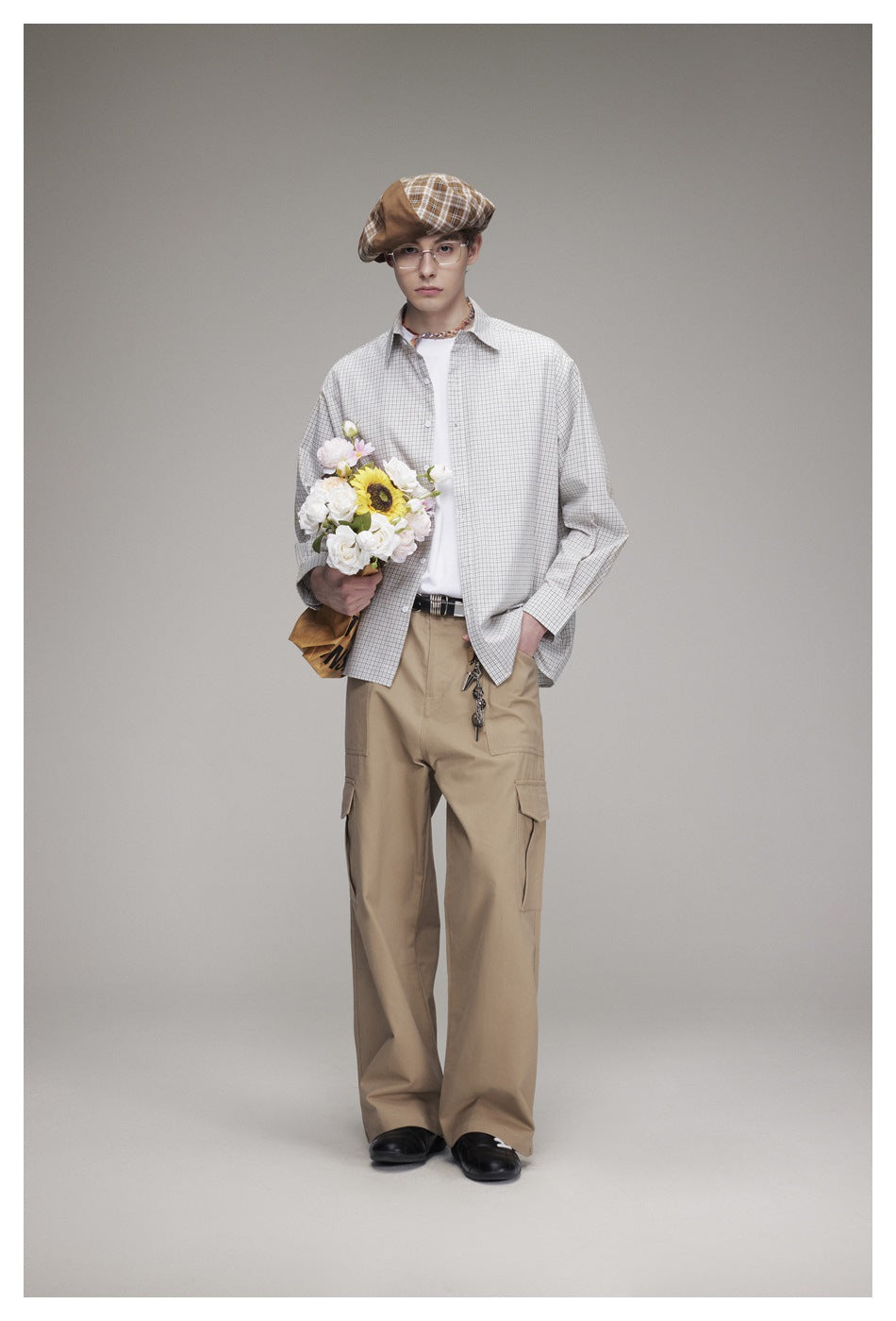 Model wearing a light gray checked button-up shirt, white tee, and loose tan cargo trousers.