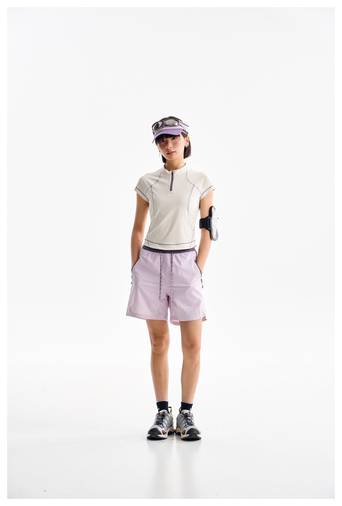 Model wearing a white zip-neck top with purple piping and lavender shorts, shown full length on white.