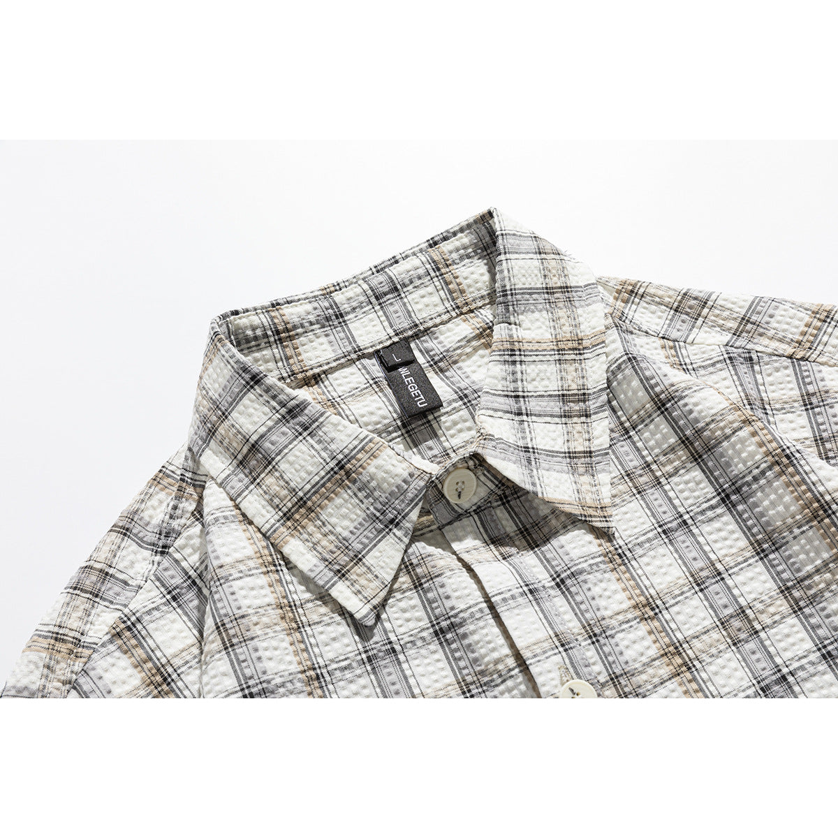 Close-up of a cream plaid shirt collar with black and tan lines, textured fabric, and a button.
