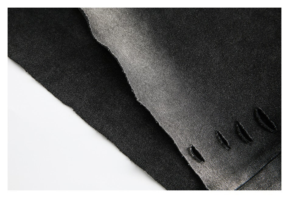 Close-up of layered black and charcoal-gray garment fabric with small slit details near the edge.