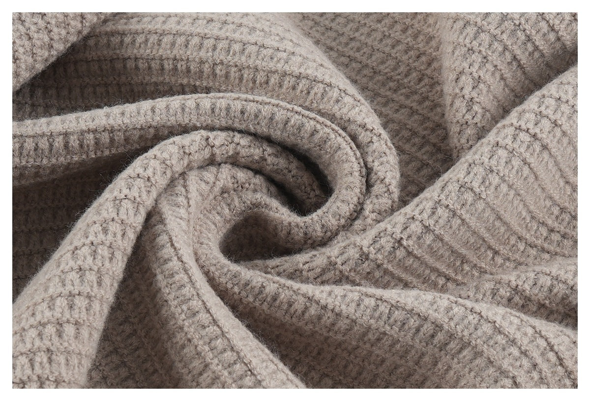 Close-up of softly folded taupe-gray knit fabric with a chunky, textured stitch.