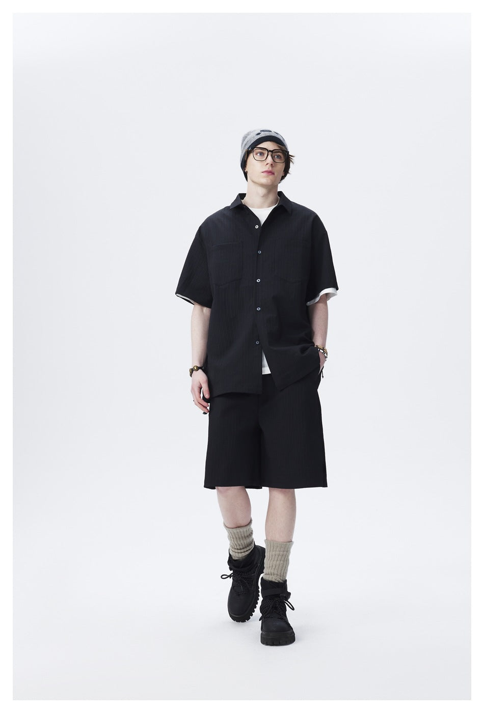 Front view of a model wearing a black short-sleeve button-up shirt and matching shorts.
