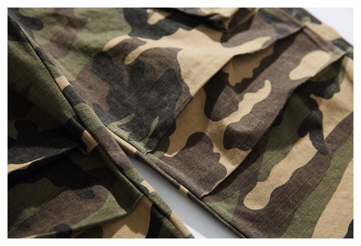 Close-up of camouflage trouser panels, seams, and a flap pocket edge.