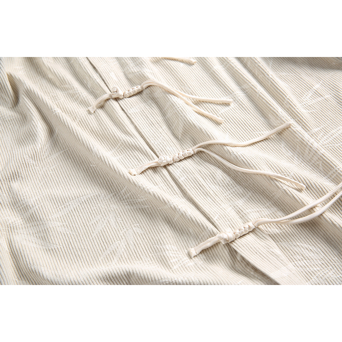 Close-up of cream ribbed fabric and three knotted tie closures.