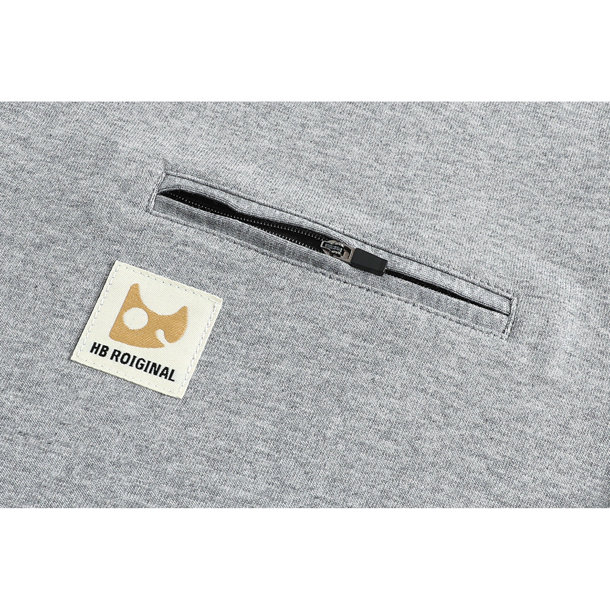 Close-up of a gray T-shirt's horizontal zip pocket and sewn-on logo patch.