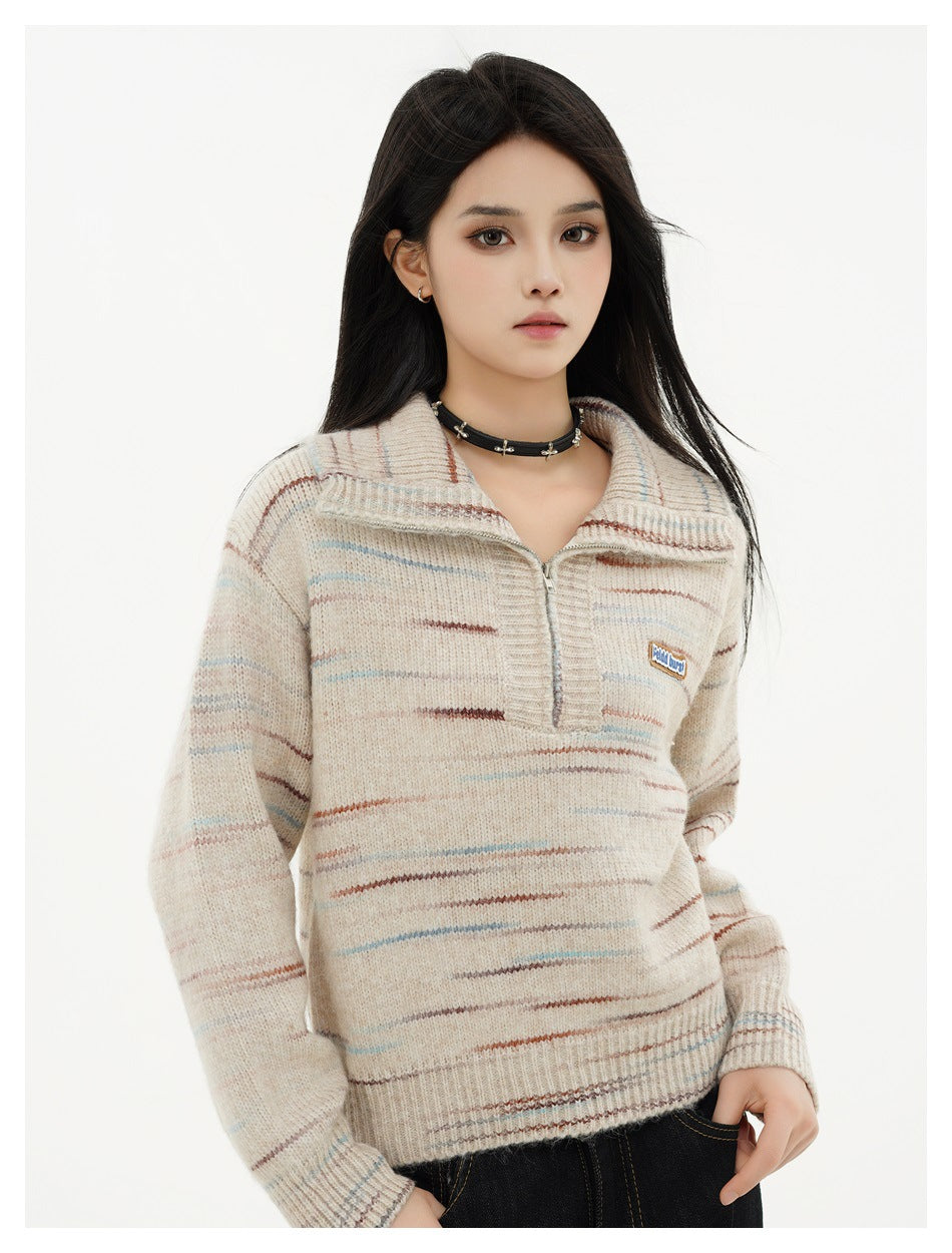 Model wearing a beige half-zip knit sweater with brown and blue streaks, front view with dark jeans
