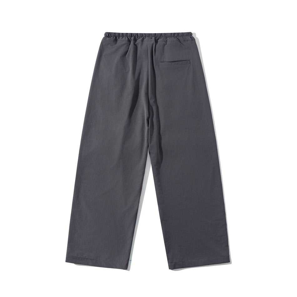 Back view of charcoal gray wide-leg trousers with an elastic waistband and one welt pocket.