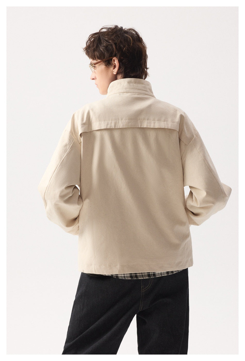Model viewed from behind in a pale beige jacket with a high collar and back yoke.