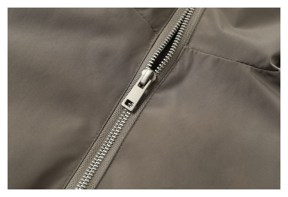 Close-up of the taupe jacket's silver metal zipper and surrounding stitching.