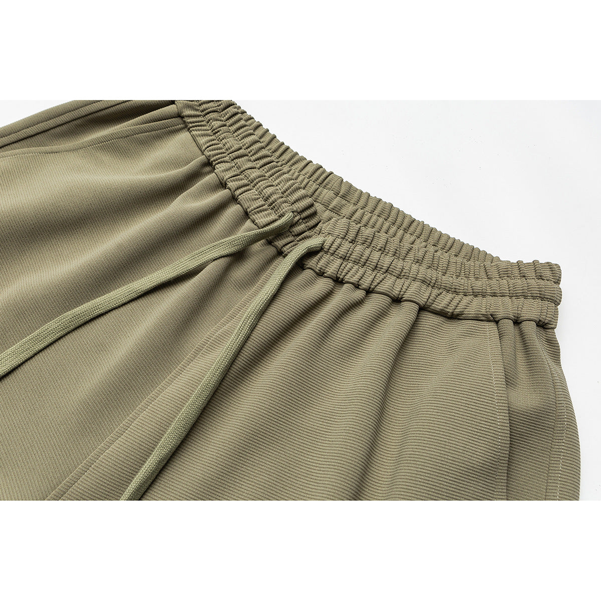Close-up of olive-khaki pants showing a gathered elastic waistband and matching drawstrings.
