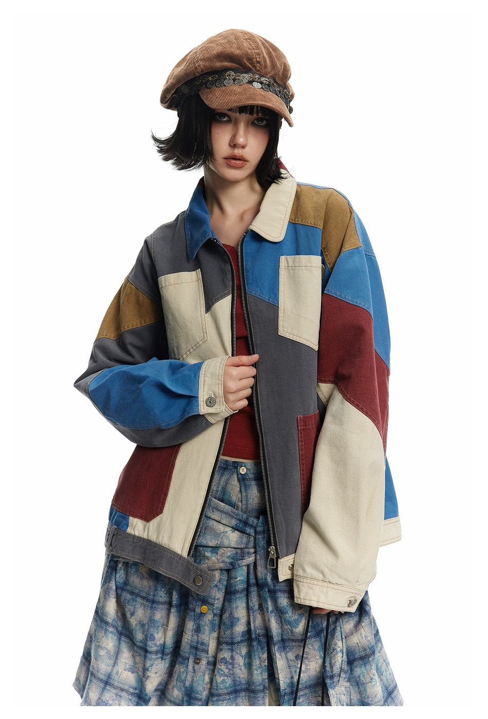 Front view of a model in a color-block patchwork jacket with cream chest pockets and a front zipper.