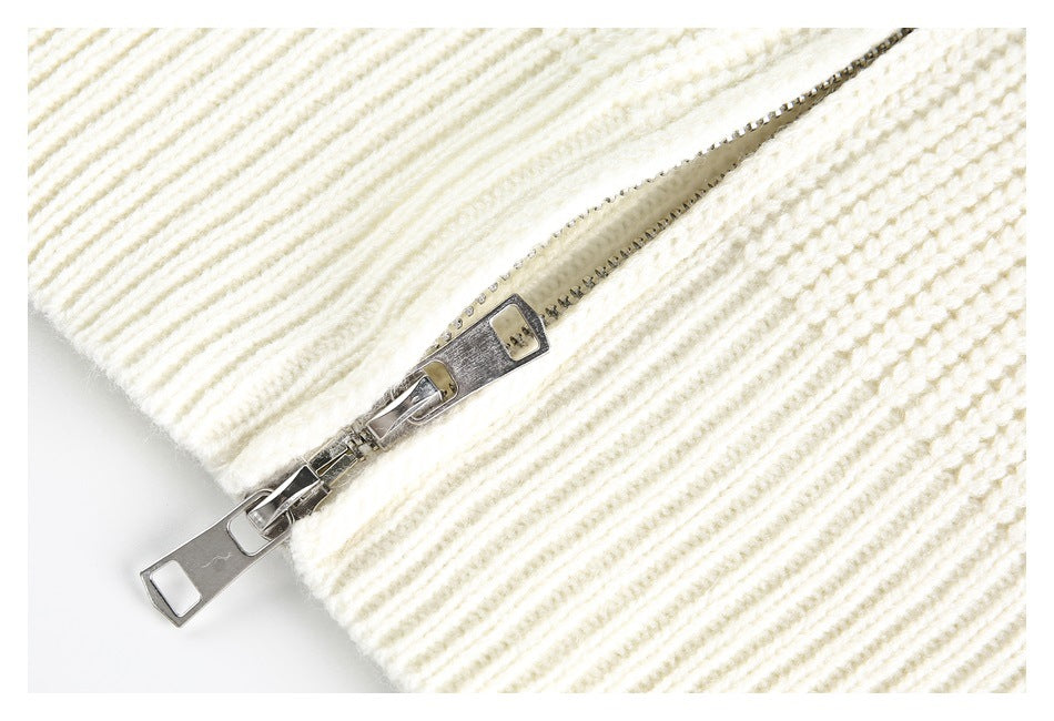 Close-up of a silver zipper on cream chunky knit fabric.