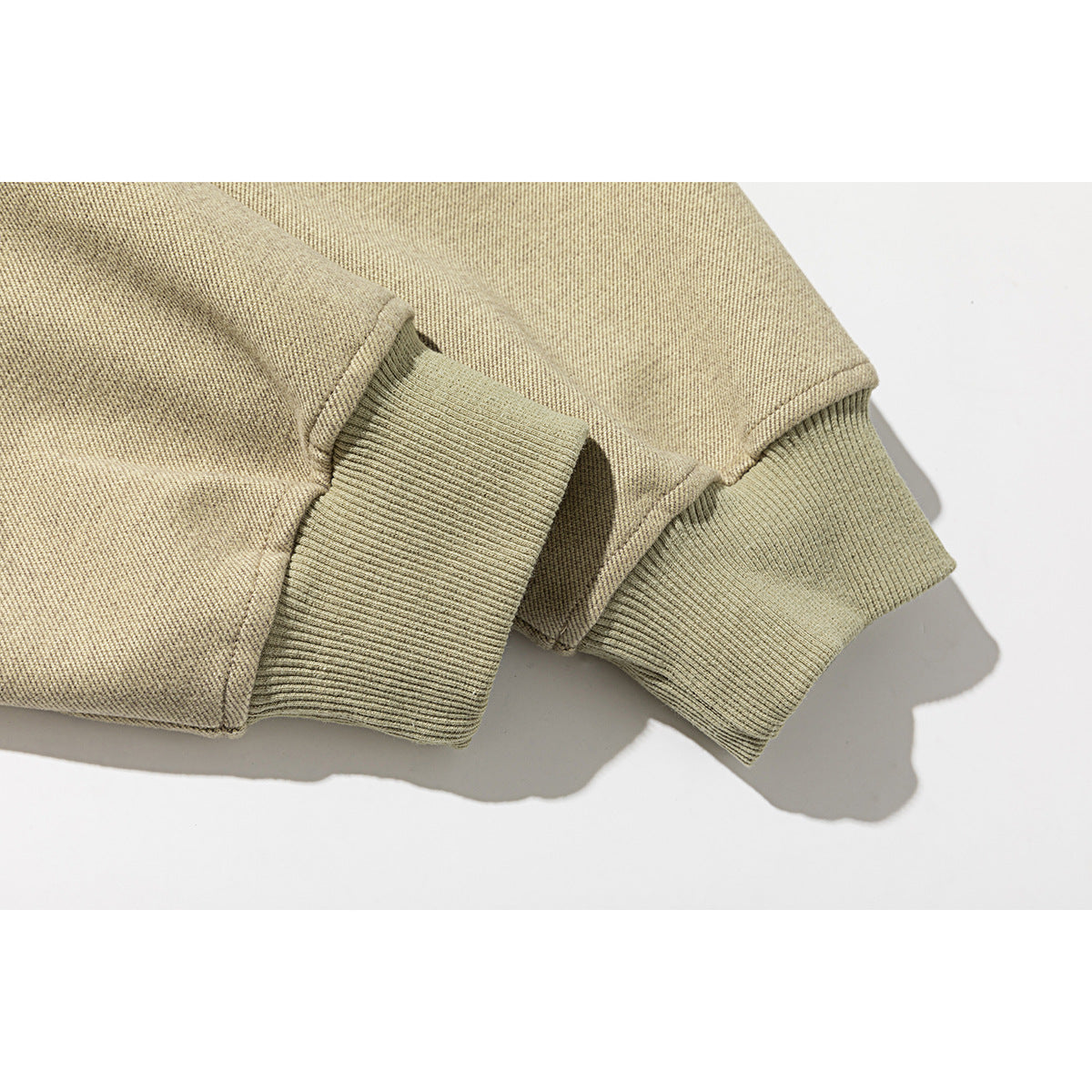 Close-up of a beige sweatshirt's folded sleeves and wide ribbed cuffs.