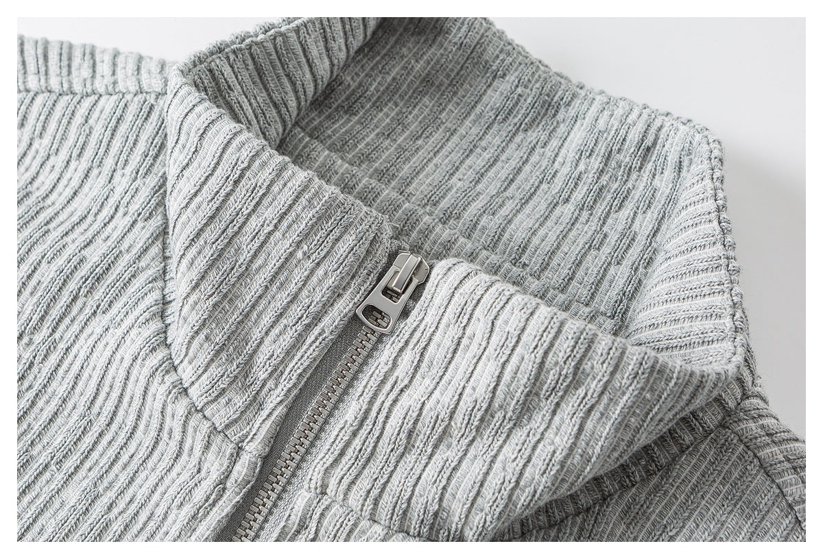 Close-up of a light gray rib-knit sweater collar and chunky metal front zipper.