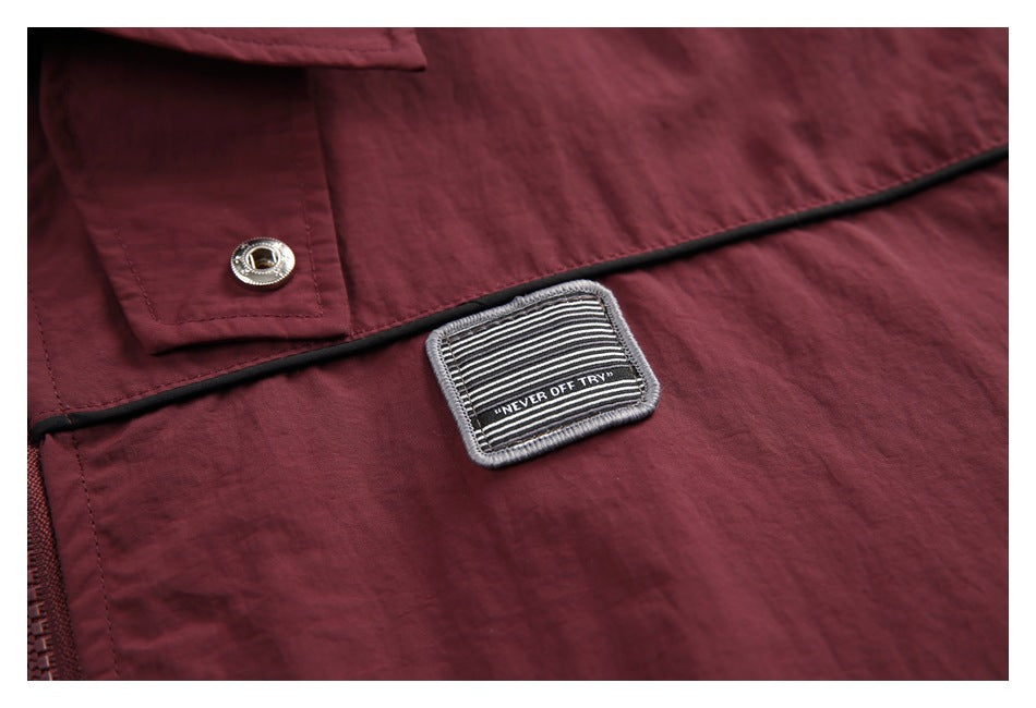 Close-up of a striped embroidered patch and snap on a burgundy jacket.