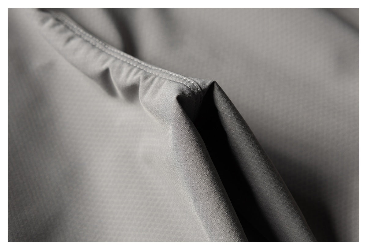 Close-up of gray garment fabric showing a stitched folded edge and subtle textured surface.