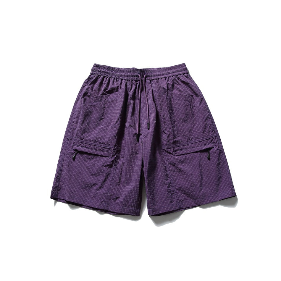 Front view of purple patterned shorts with an elastic drawstring waist and two large flap cargo pockets.