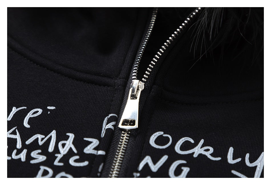 Close-up of the silver zipper and handwritten-style graphic on the black hoodie, with feather trim at the edge.