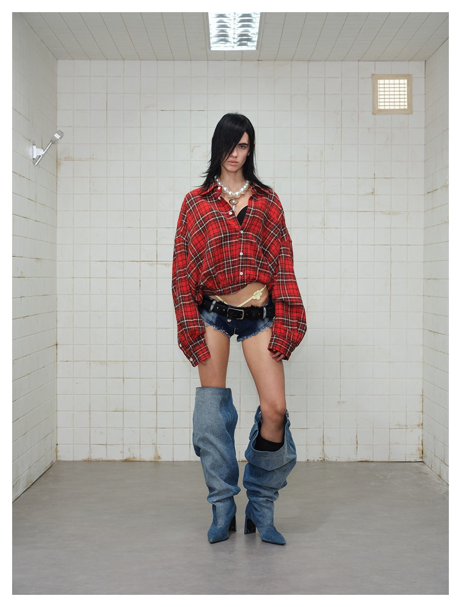 Model wearing a red plaid cropped shirt jacket, unbuttoned at the top, in a tiled room, front view