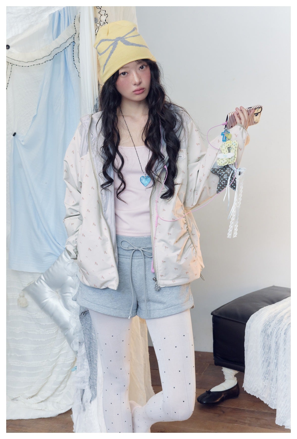 Closer view of a model wearing an off-white printed hooded jacket over a pale pink top and gray shorts.