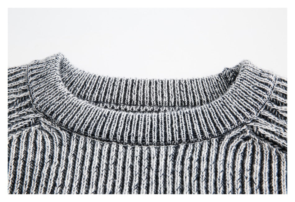 Close-up of the ribbed crewneck and raglan shoulder stitching on a gray marled sweater.