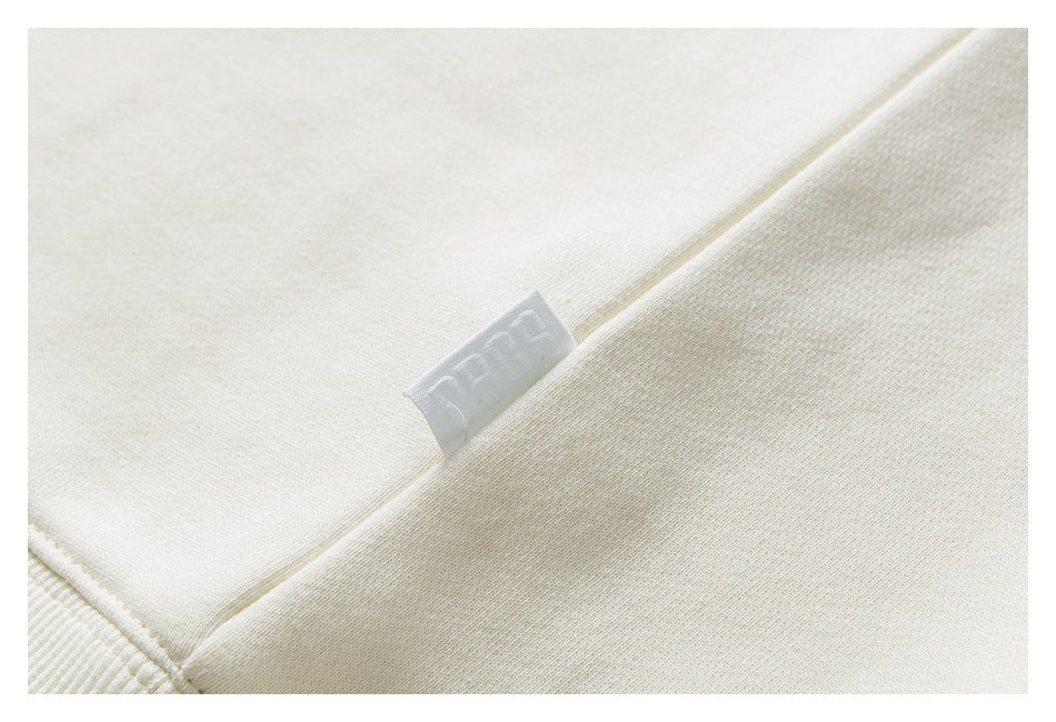 Close-up of cream sweatshirt fabric and a small sewn-in white label.