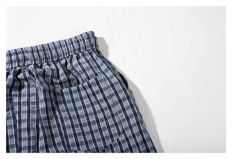Close-up of a front pocket and elastic waistband on blue-gray vertically striped shorts.