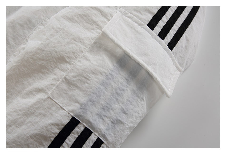 Close-up of a white garment with a flap pocket and three black stripes.