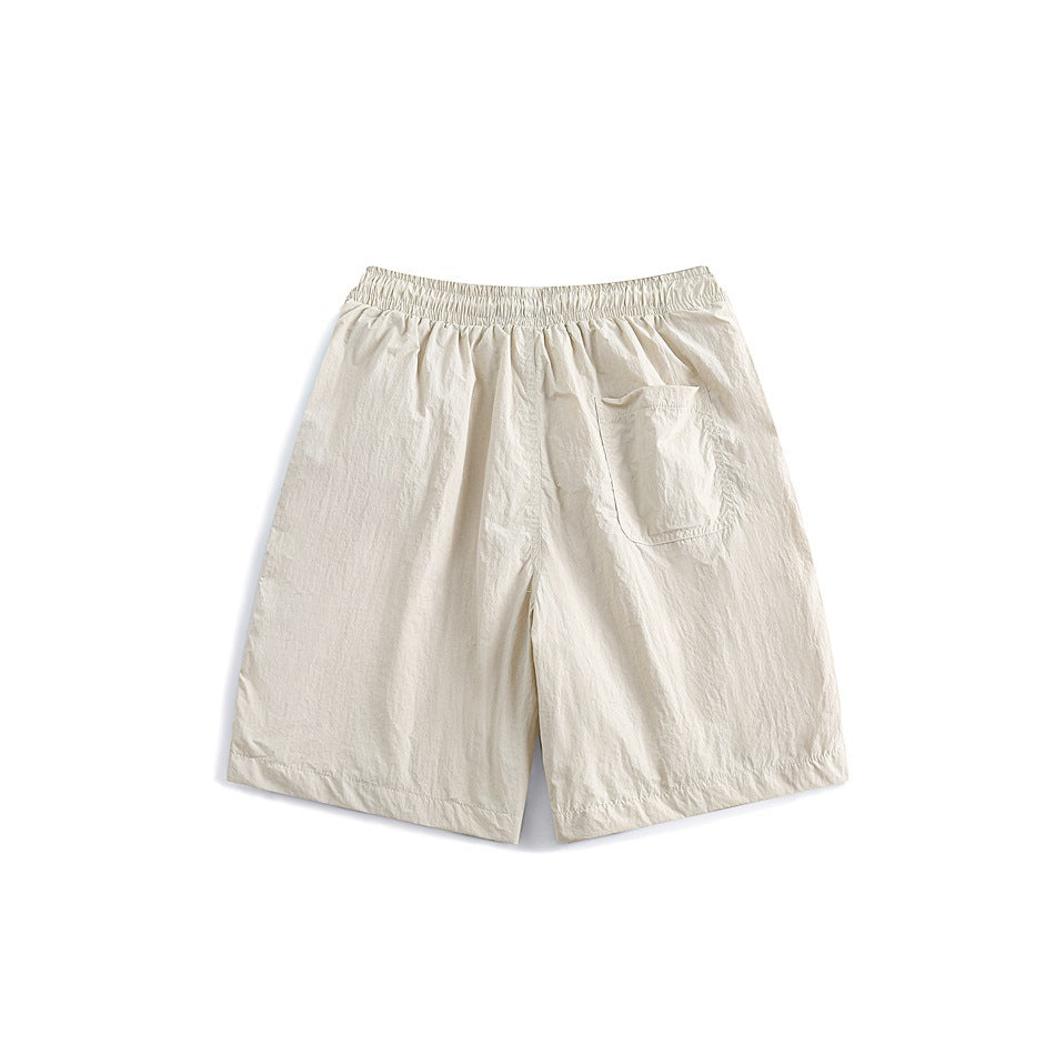 Back view of cream shorts with an elastic waistband and a single patch pocket.