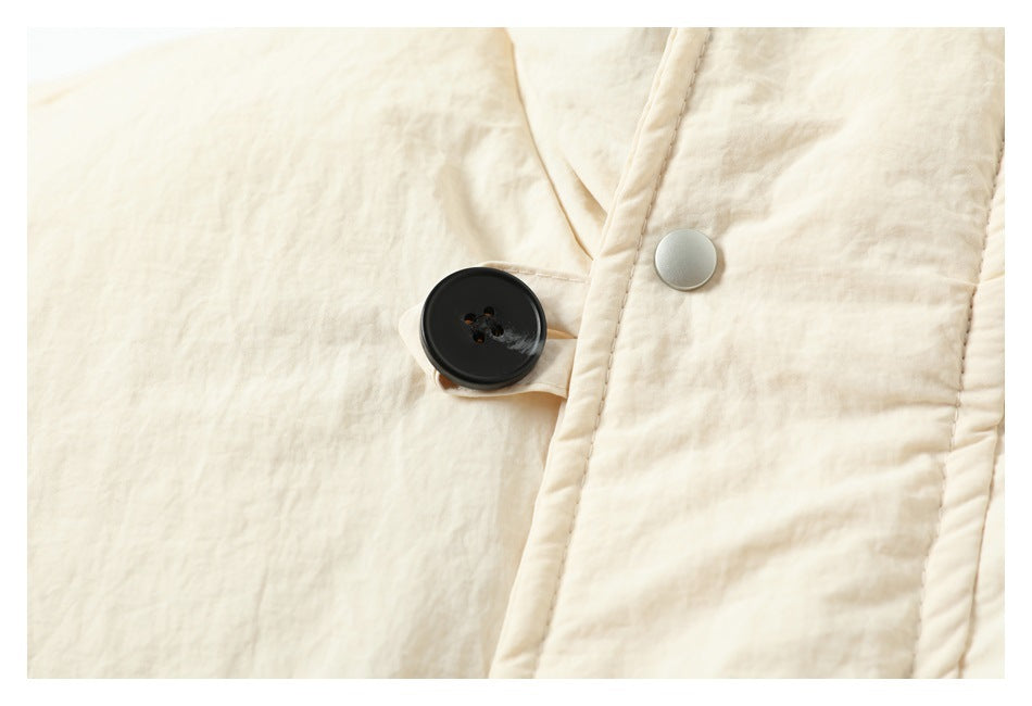 Close-up of the ivory jacket's large black button and silver snap on the front placket.
