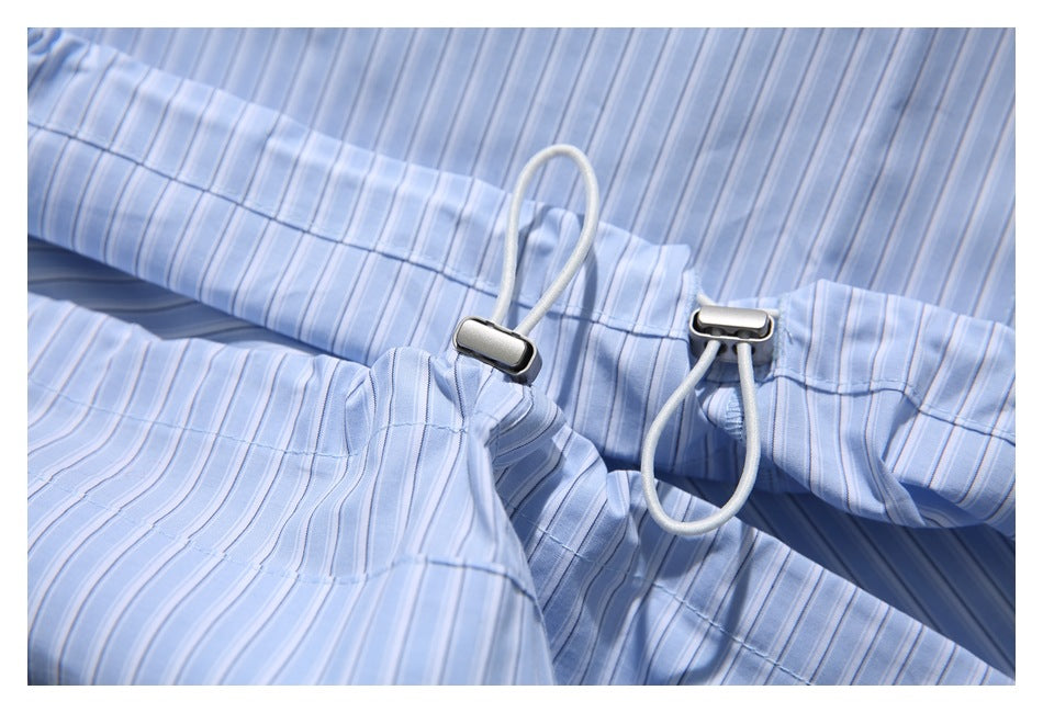 Close-up of a light blue striped garment waistband with an adjustable cord and metal toggles.