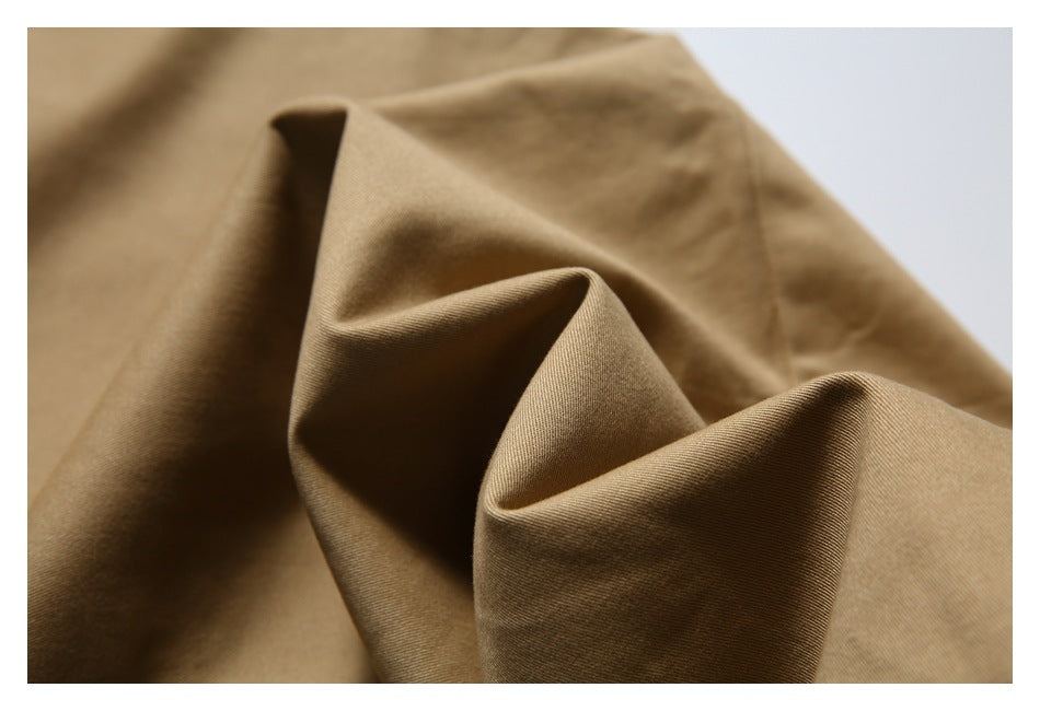 Close-up of tan garment fabric folded into soft ridges, showing its surface texture.