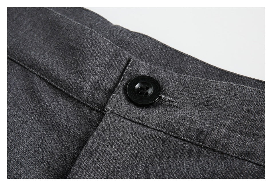 Close-up of charcoal gray trousers showing the waistband button, buttonhole, and seams.