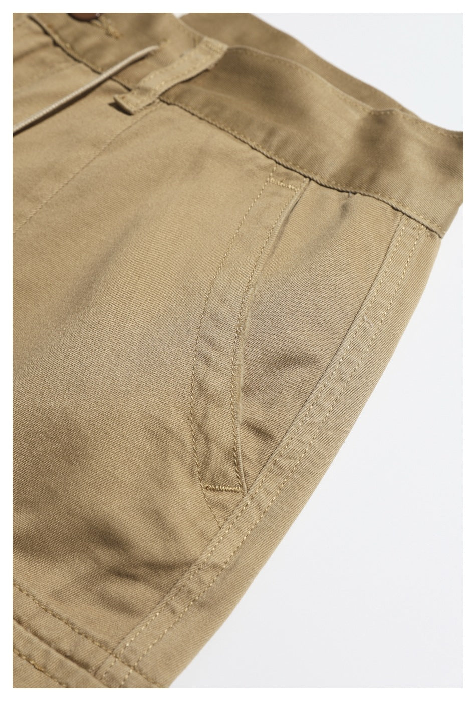 Close-up of khaki trousers showing a slanted side pocket and reinforced stitching.
