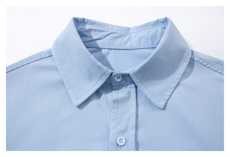 Close-up of a light blue shirt collar, shoulder seams, and buttoned front placket.